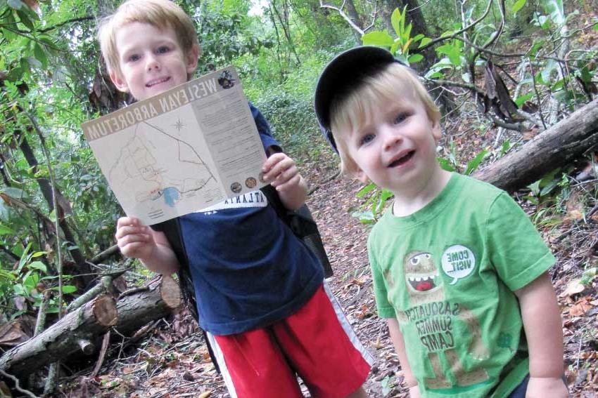 两个男孩在植物园里徒步旅行，手里拿着地图
